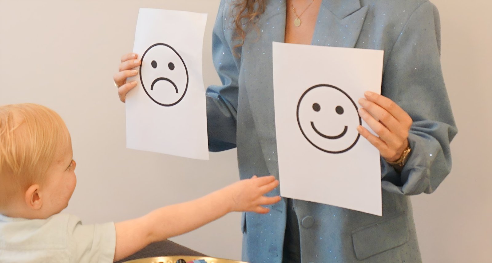 Therapeut houdt een blije smiley omhoog bij een jong kind